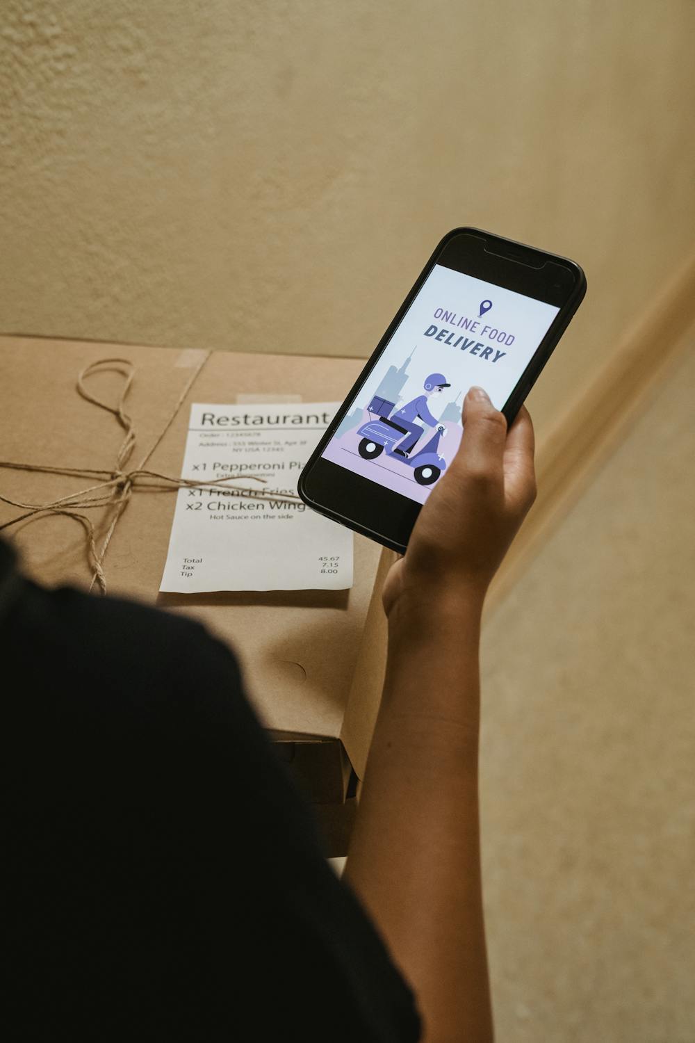 Pessoa segurando celular com pedido de delivery ao lado de embalagens de restaurante