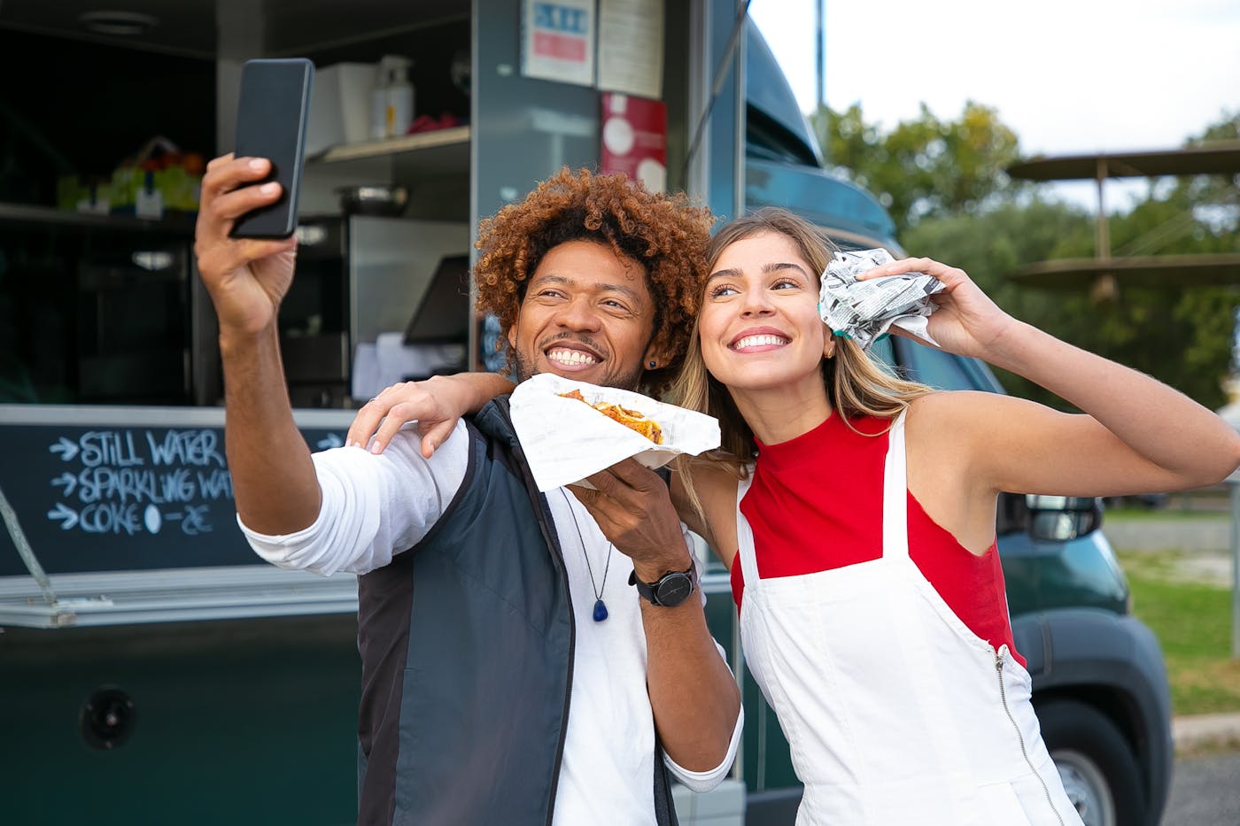 Clientes felizes comendo e usando celular em frente a um food truck